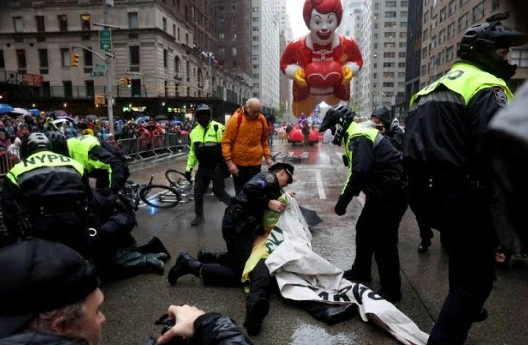 Macy's parade in NYC. Giant fucking Ronald McDonald floats in the background, holding a heart, while anti-genocide protestors are being tackled